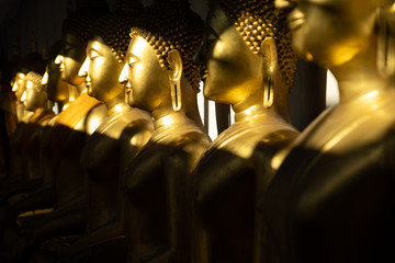 close up row of golden buddha statue in the light and shadow of sun at Wat Pra Sri Mahathat temple,...