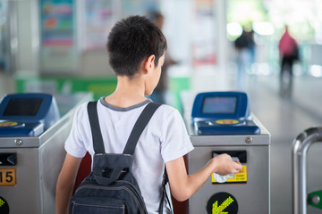 Little student boy use a ticket entrance to the railway station