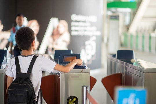 Little student boy use a ticket entrance to the railway station - Powered by Adobe