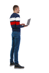 Back view of a man who is standing with a laptop.