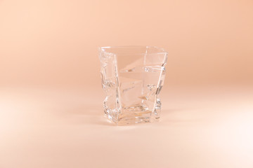 An empty glass is standing on a pink surface