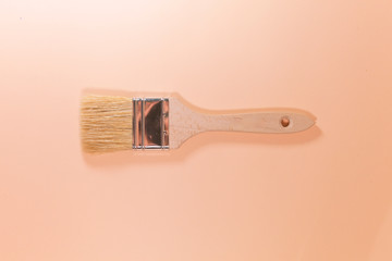 A brown paintbrush is laying on a pink surface