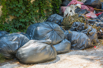 Bunch of black bags with rubbish lying on street.