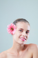 Fototapeta na wymiar Portrait of attractive happy pretty woman with beautiful flower in her hair smiling at camera