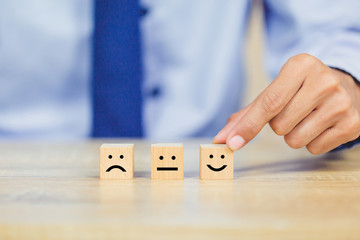 customer pressing smiley face emoticon on wood cube, Service rating, satisfaction concept.