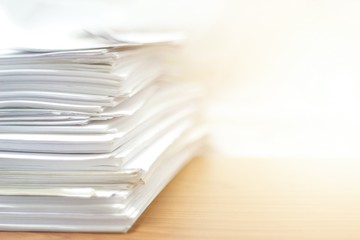Paper stack on desk related to business functions. Paper-related work on the table.