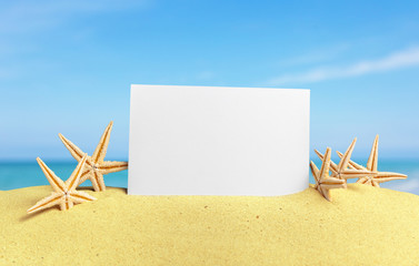 Seashells with blank card on sand beach