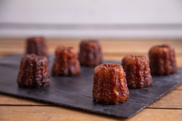 French pastry Caneles de bordeaux rum and vanilla flavor thick caramelized crust on black slate plate..