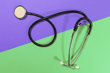 A stethoscope is laying on a purple and green surface