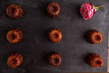 French pastry Caneles de bordeaux rum and vanilla flavor thick caramelized crust on black slate plate..