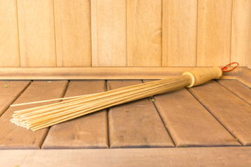 Bamboo broom lies on the shelf in the sauna
