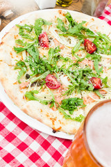 Homemade italian pizza, fresh cherry tomatoes and basil, arugula served on wooden board