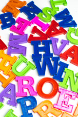 Heap of plastic colored alphabet letters close up.
