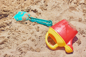 Childrens toys watering can for watering and shovel lies in sandbox.