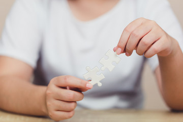 Close-up hand place a piece of white jigsaw puzzle on a blue background made of white per piece and place it for your content