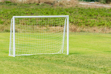 Football goal with net for playing on green grass.