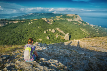 Naklejka na ściany i meble Young girl hiker sitting on a stone