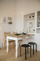 Decorated with lights room and festive table serving in Christmas tradition  