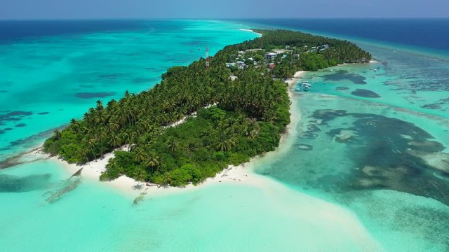 Aerial view of a tropical island with a forest and city on it. In turquoise blue water of the sea in Bali. Slight pedestal up.