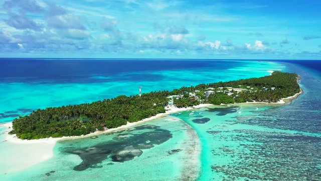 Aerial view of a tropical island with a forest and village and radio mast on it. In the turquoise sea in Bali. Next to a reef. Dolly in