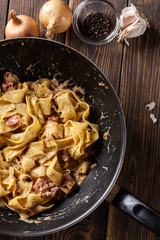 Pappardelle pasta with prosciutto and cheese sauce on pan