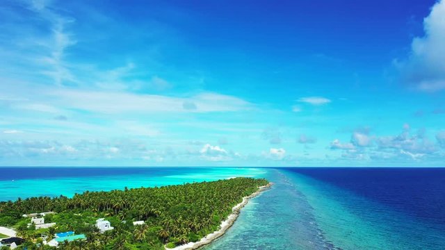 Aerial view along a tropical island with a forest and village on it. In the turquoise and blue Sea in Bali.Sligth dolly out.