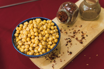 Yellow chickpeas lie in an oriental plate on a wooden spice board