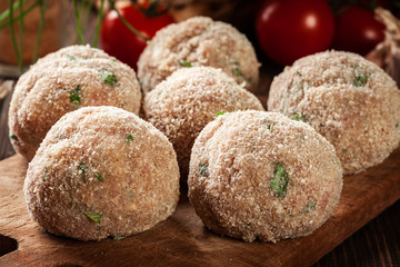 Raw meatballs rolled in a crispy bun prepared for baking