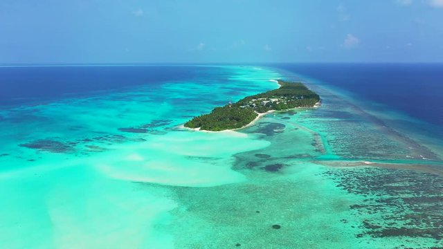 Aerial view of the sea in Bali. Turquoise water with sandbanks,reef and an island with trees and an island. dolly in