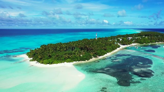 Aerial view of a tropical island with a forest and village on it. Surrounded by the turquoise and blue sea in the Gulf of Thailand. Reefs in the water.