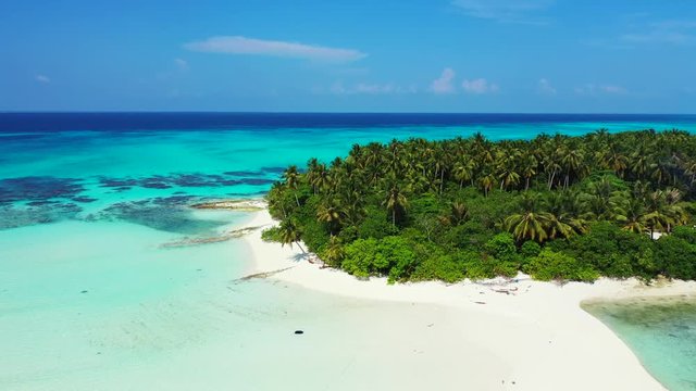 Aerial view of a tropical island with palm trees on it. In the turquoise sea in Hawaii. Dolly out reveals a sandbank in front of the isle and an antenna on it