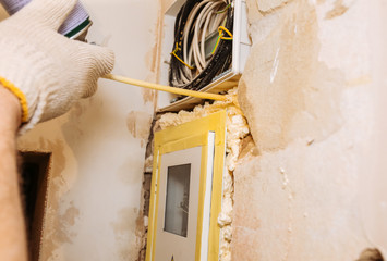 Worker is filling spray foam near electrical panel. Maintenance repair works renovation in the...