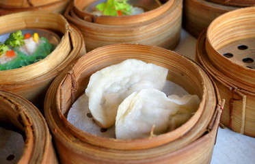 Close up Chinese gyoza steamed dumplings in bamboo basket in dim sum set