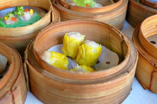 Close up Cantonese Shumai (Siu Mai) Dim Sum, shrimp & pork Chinese steamed dumplings wrap by yellow wonton wrapper (Kanom Jeeb in Thai) in bamboo basket in dim sum set