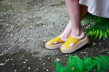 Women's legs in stylish summer sandals with straw soles, concept of comfortable shoes, side view