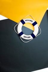 Top down view Welcome Aboard Lifebuoy on a yellow paper photographic studio background