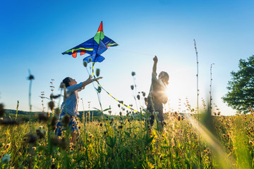 young happy beautiful couple flying a kite in a summer field, summer happiness and love concept
