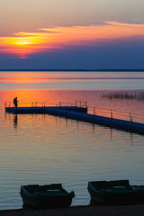 Fototapeta na wymiar men on pontoon pier at sunset