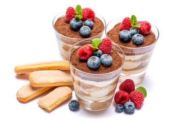 Classic tiramisu dessert with blueberries and raspberries in a glass and savoiardi cookies isolated on a white background with clipping path