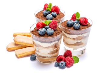Classic tiramisu dessert with blueberries and raspberries in a glass and savoiardi cookies isolated on a white background with clipping path