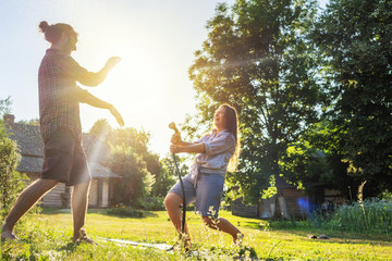 young happy beautiful couple hosing in the garden, summer happiness and love concept