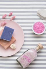 Spa therapy. Natural body care products. Flat lay arrangement of pink bath salt and soap on striped background.