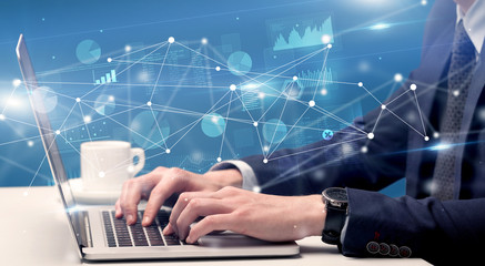 Businessman typing on laptop with linked reports charts grapghs around
