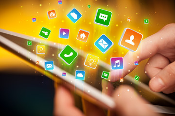 Businessman hand using tablet with flying application icons around
