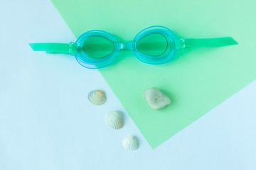 Summer flatlay with watersport goggles, mint and light blue background, minimalistic style, copy space.