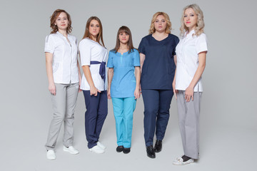 Fototapeta premium Successful team of medical doctors are looking at camera while standing on grey background