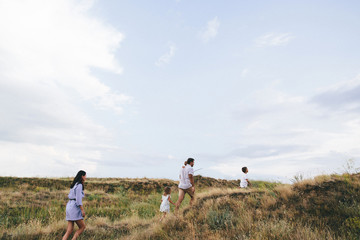 Happy parents and children are walking outdoors in a wheat field view.