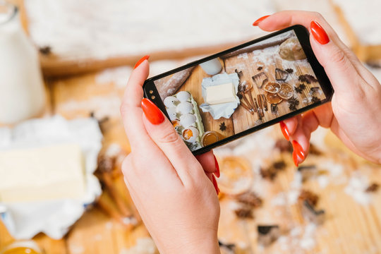 Gingerbread biscuit recipe. Lady using smartphone to take picture of pastry ingredients.