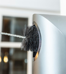 Chimney sweep cleaning a chimney standing balanced on the apex of a house roof lowering equipment down the flue