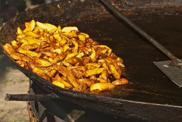 Roast potatoes in a large pan. Delicious food at the festival. Field kitchen at the hearth.